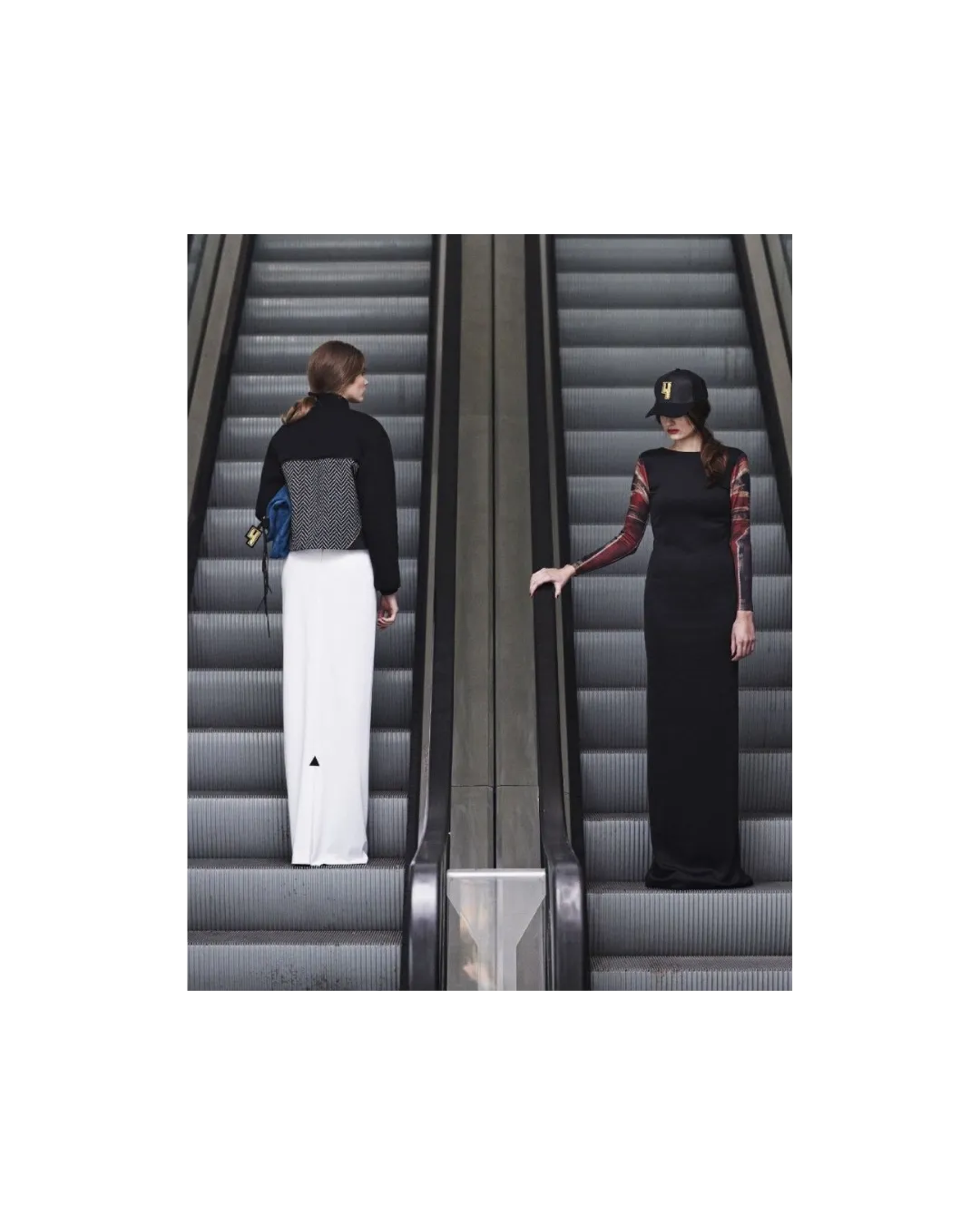 Two figures on escalators in contrasting black and white